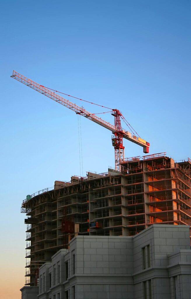 A construction crane at a commercial building site showcasing progress on a high-rise project under clear blue skies. 