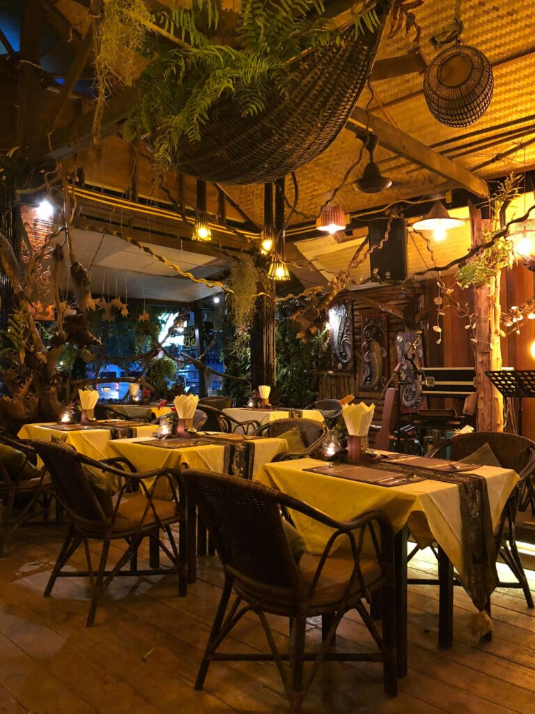 Cozy restaurant interior with warmly lit tables set for dining, featuring rustic decor and a welcoming ambiance for guests.